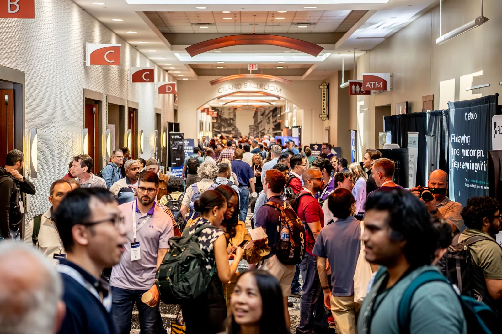 A busy conference hallway filled with attendees talking between sessions at All Things AI 2026