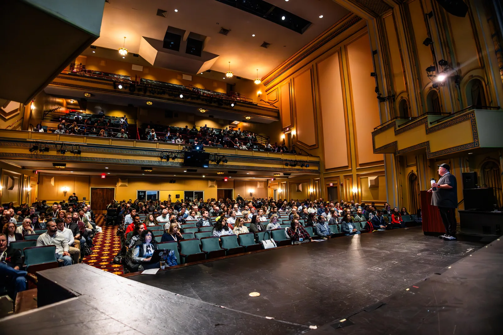 A speaker on the Carolina Theatre’s main stage facing a full audience and balconies at the 2025 conference